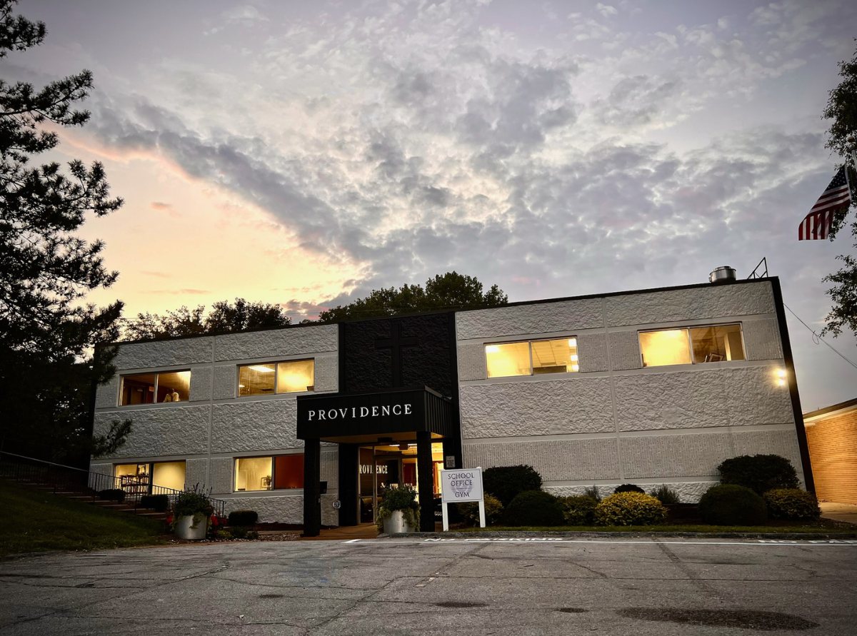 The Providence Academy building at dusk with its windows lit