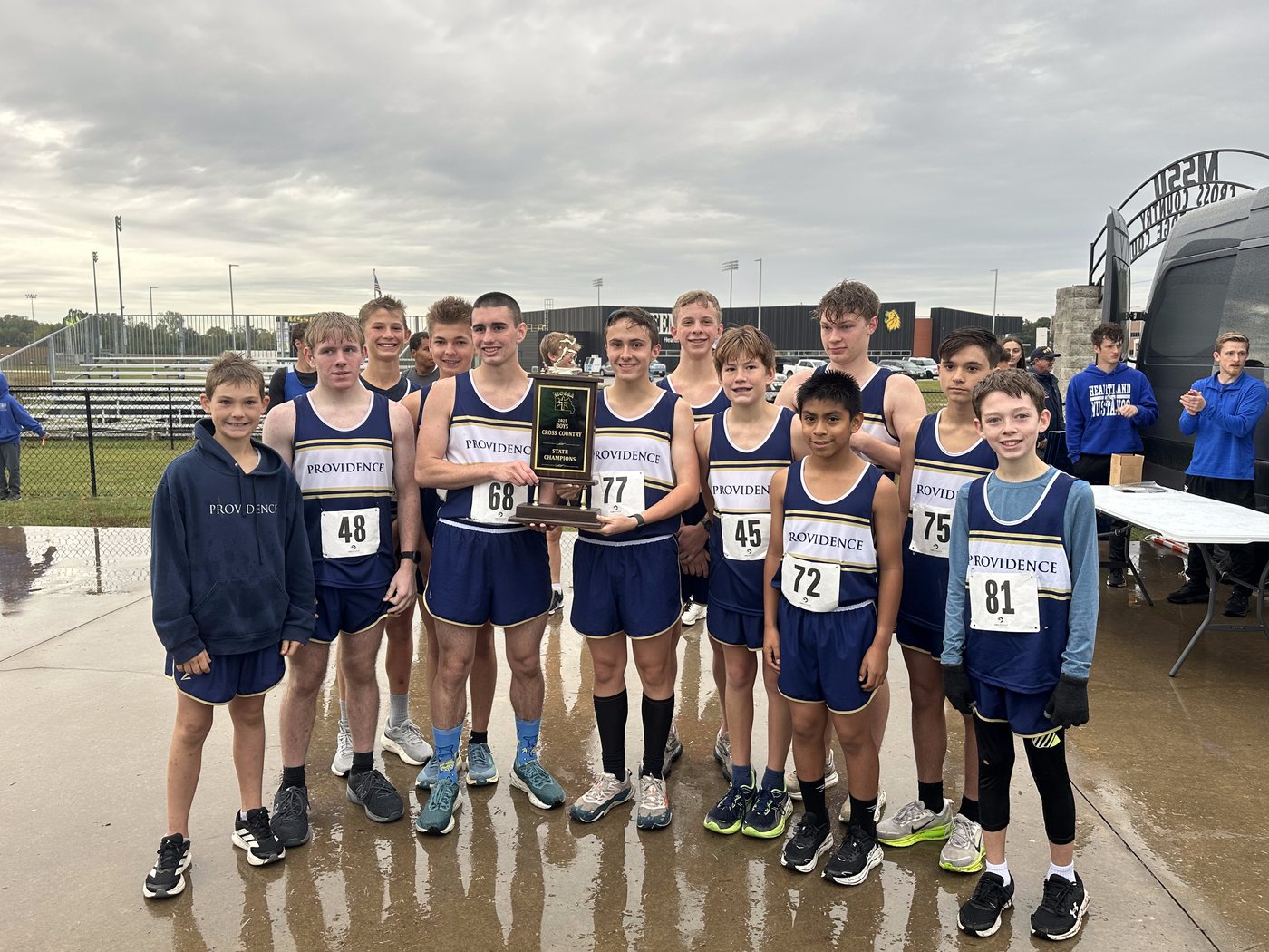 The Providence boys cross country team holding the 2025 state championship trophy