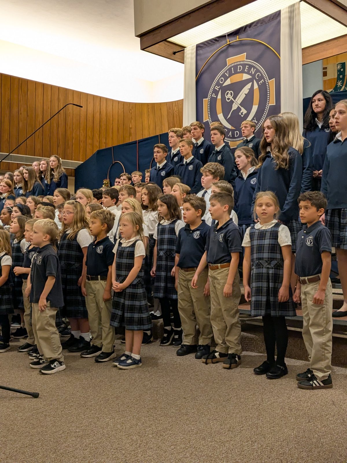 Providence students from preschool through high school singing together beneath the school crest at the Harvest Festival